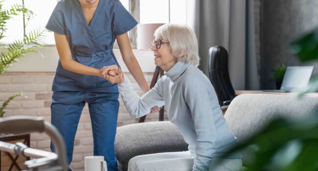 Professional caregiver taking care of elderly woman at home